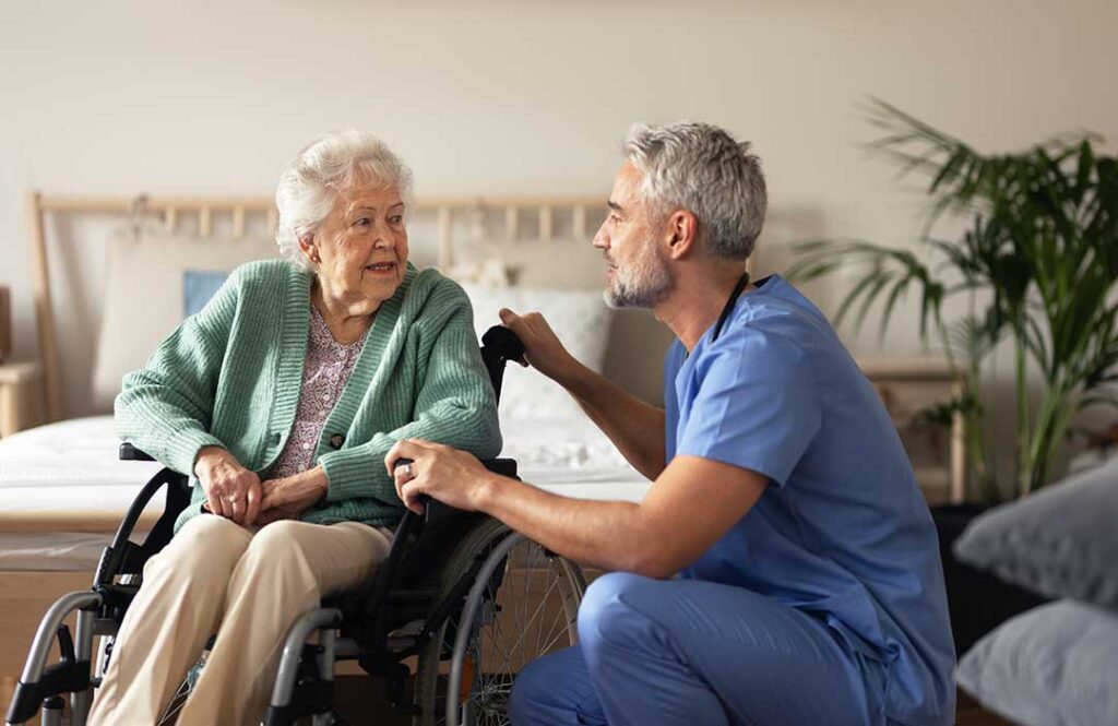 Older adult reviewing medications with a caregiver at a dining table in an assisted living residence.